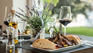 Rippchen mit Weißbrot und einem Rotwein auf einem gedeckten Tisch