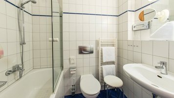 Badewanne mit Dusche, Toilette und Waschbecken in einem Bad